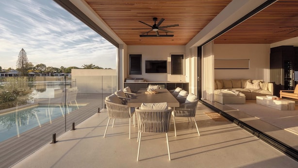 Un espacio de estar moderno con piscina, mobiliario exterior y un televisor de pantalla plana grande.