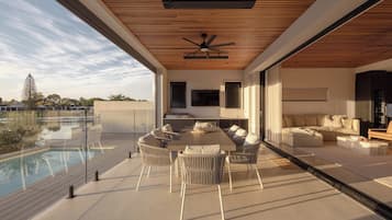 A modern living space with a pool, outdoor furniture, and a large flat-screen TV.