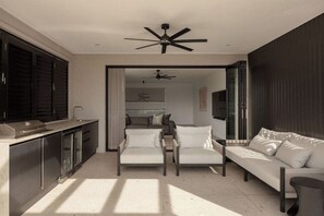 Ein moderner Wohnraum mit Sofa, Stühlen, Deckenventilator und Küchenzeile.