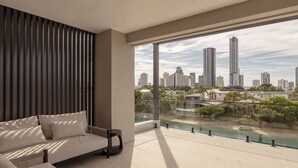 A balcony with a city view, a sofa, and a railing. - Maison by Khove (Broadbeach Waters)