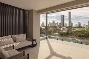 Un balcón con vista a la ciudad, un sofá y una barandilla.