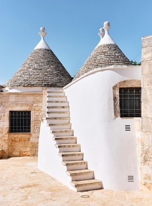 A building with two conical roofs, a staircase leading to a door, and a stone wall. - Trulli with swimming pool in the heart of Itria Valley (Martina Franca)