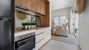 Eine moderne Küche mit eingebauten Geräten, einer Holz Arbeitsplatte und Blick zum Wohnbereich.