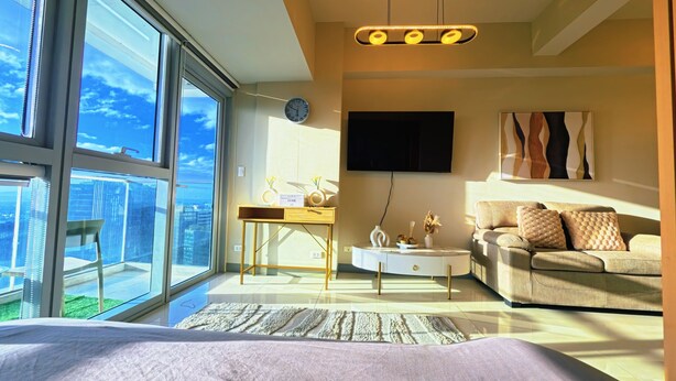 A modern bedroom with a large bed, a sofa, a coffee table, and a desk with a TV and decorative items.