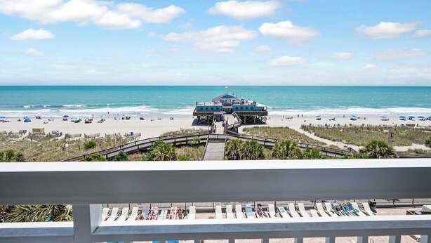 A beach view with a lifeguard tower, beach umbrellas, and lounge chairs. - Amazing Large Private Studio Condo with Amazing View (Myrtle Beach)