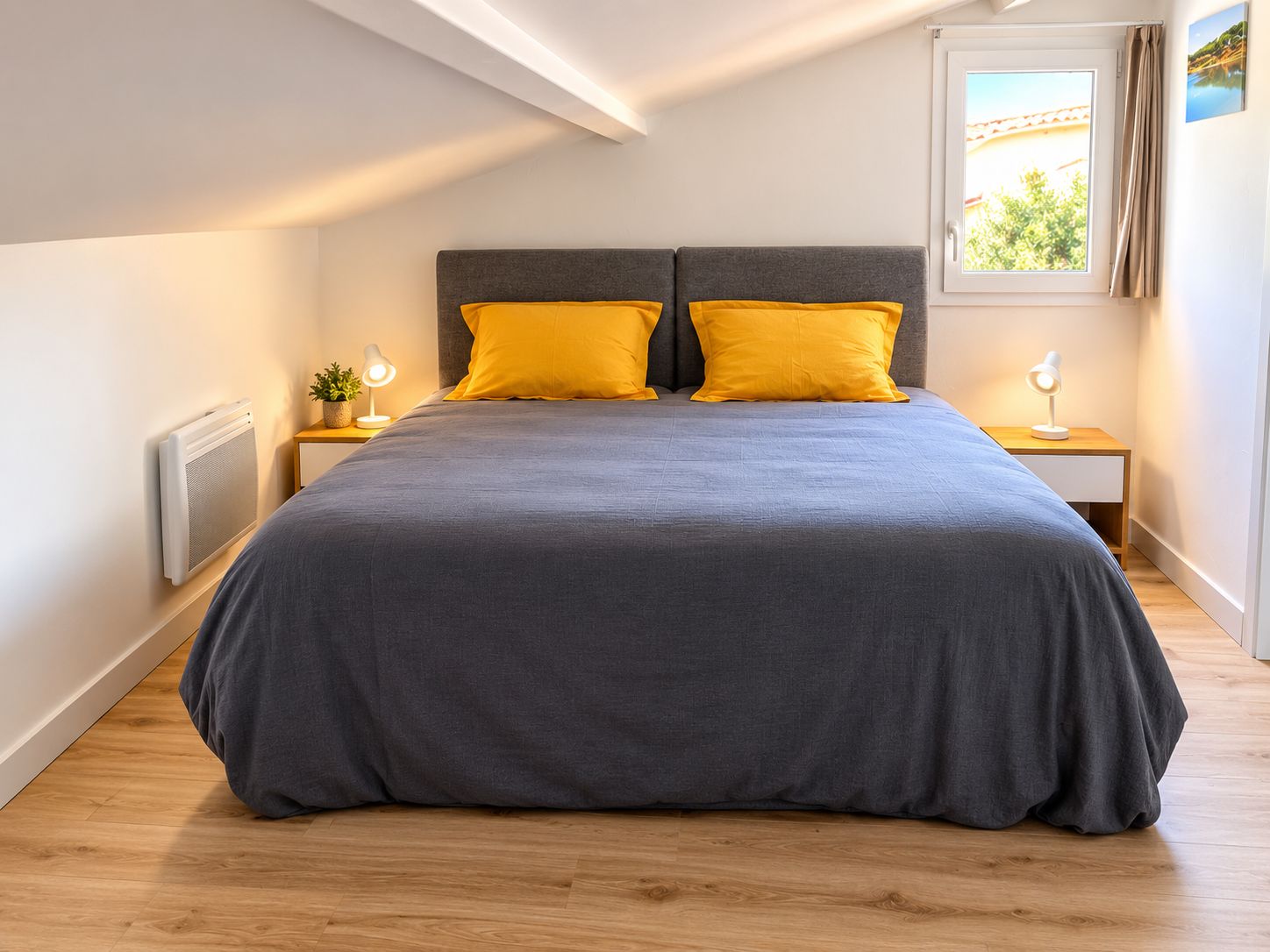 Une chambre à coucher avec un grand lit, deux tables de chevet, un radiateur et une fenêtre avec des rideaux.