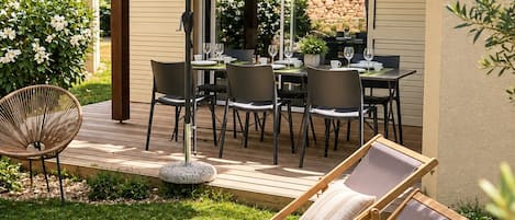 A patio with a table and chairs, a lounge chair, and a pergola with an umbrella.
