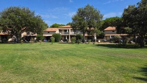 Um pátio com gramado, árvores e edifícios com telhados de cerâmica.