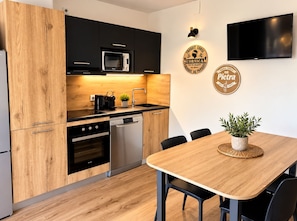 Une cuisine moderne dotée de meubles en bois, d’un four à micro-ondes, d’un lave-vaisselle et d’un coin repas avec une table et des chaises.