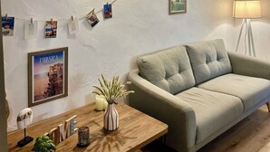 Uma sala de estar moderna com um sofá, uma mesa de madeira com uma planta e luminárias fixadas na parede.