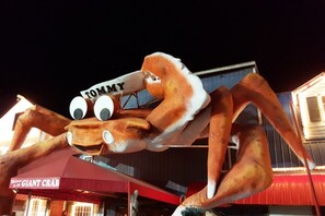 A large crab mascot with a sign that reads 'TOMMY' in front of a building with a sign that says 'GIANT CRAB.'