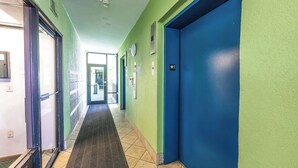 A hallway with green walls, blue doors, and a tiled floor.
