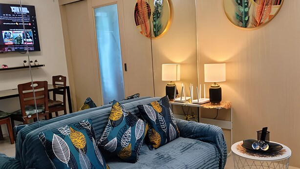 Ein modernes Wohnzimmer mit einem blauen Sofa, dekorativen Kissen, einem runden Couchtisch und Wandbildern.