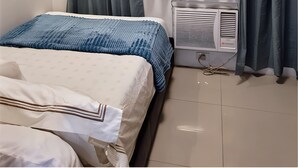 Ein Schlafzimmer mit einem Bett, einem Nachttisch, einem Heizgerät und Vorhängen.