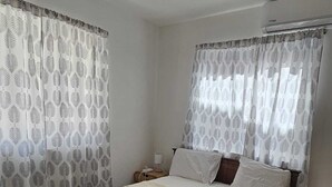 Een slaapkamer met een groot bed, twee nachtkastjes, een venster met patroon gordijnen.