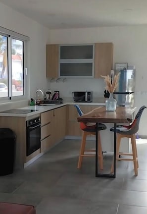 Una cocina moderna con comedor, que incluye un microondas, pileta y armarios.