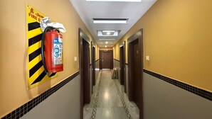 Un passadís d'hotel amb un extintor fixat a la paret, portes a banda i banda, i un sòl de rajola.