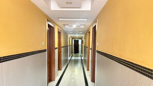 A hotel corridor with a tiled floor, wooden doors, and a ceiling with recessed lighting. - Hotel South Avenue (Tirunelveli)