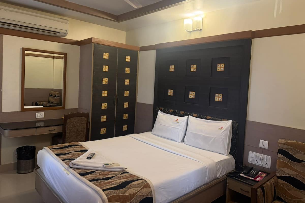 Una habitación de hotel con cama, escritorio, silla, armario y ventilador de techo.