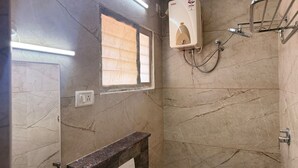 Un bany amb dutxa, una finestra i un penjador de tovalloles.