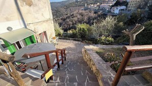 A stone staircase leading to a terrace with a table and chairs, overlooking a hillside village. - Casa Comandante – Two-Level Apartment with Sea View in Marciana (Marciana)