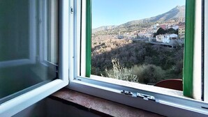 A window with a view of a hillside town, a clear sky, and a mountain in the distance. - Casa Comandante – Two-Level Apartment with Sea View in Marciana (Marciana)