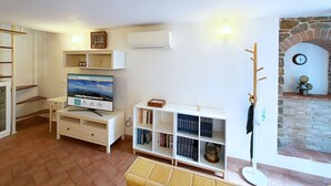 A living room with a television, bookshelves, a fireplace, and a coat rack. - Casa Comandante – Two-Level Apartment with Sea View in Marciana (Marciana)
