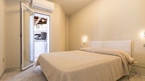 A bedroom with a bed, an air conditioning unit, and a door leading to a balcony. - VILLA RITTER ORIZZONTE (Marina di Campo)
