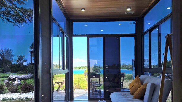 A modern interior with large windows, a sofa, and a table. - Nawesa Resort (Rentapow)