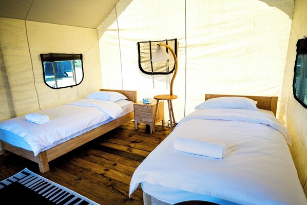 A tent-style room with two beds, a small table, and a chair. - Nawesa Resort (Rentapow)