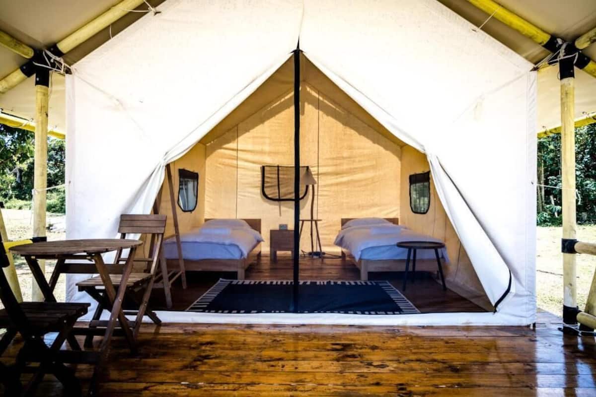 A tent with two beds, a table, and a chair.