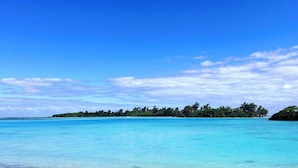 A clear blue sky and calm turquoise sea with a distant tree-covered island. - Nawesa Resort (Rentapow)