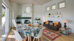 Un comedor con una mesa preparada para cuatro, un sofá y un televisor al fondo.