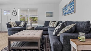 Ein Wohnzimmer mit zwei Sofas, einem Couchtisch, einem kleinen Beistelltisch und einem Fenster mit Jalousien.