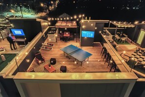 Eine Terrasse im Freien mit einem Tischtennisschläger, Sitzgelegenheiten und Lichterketten.