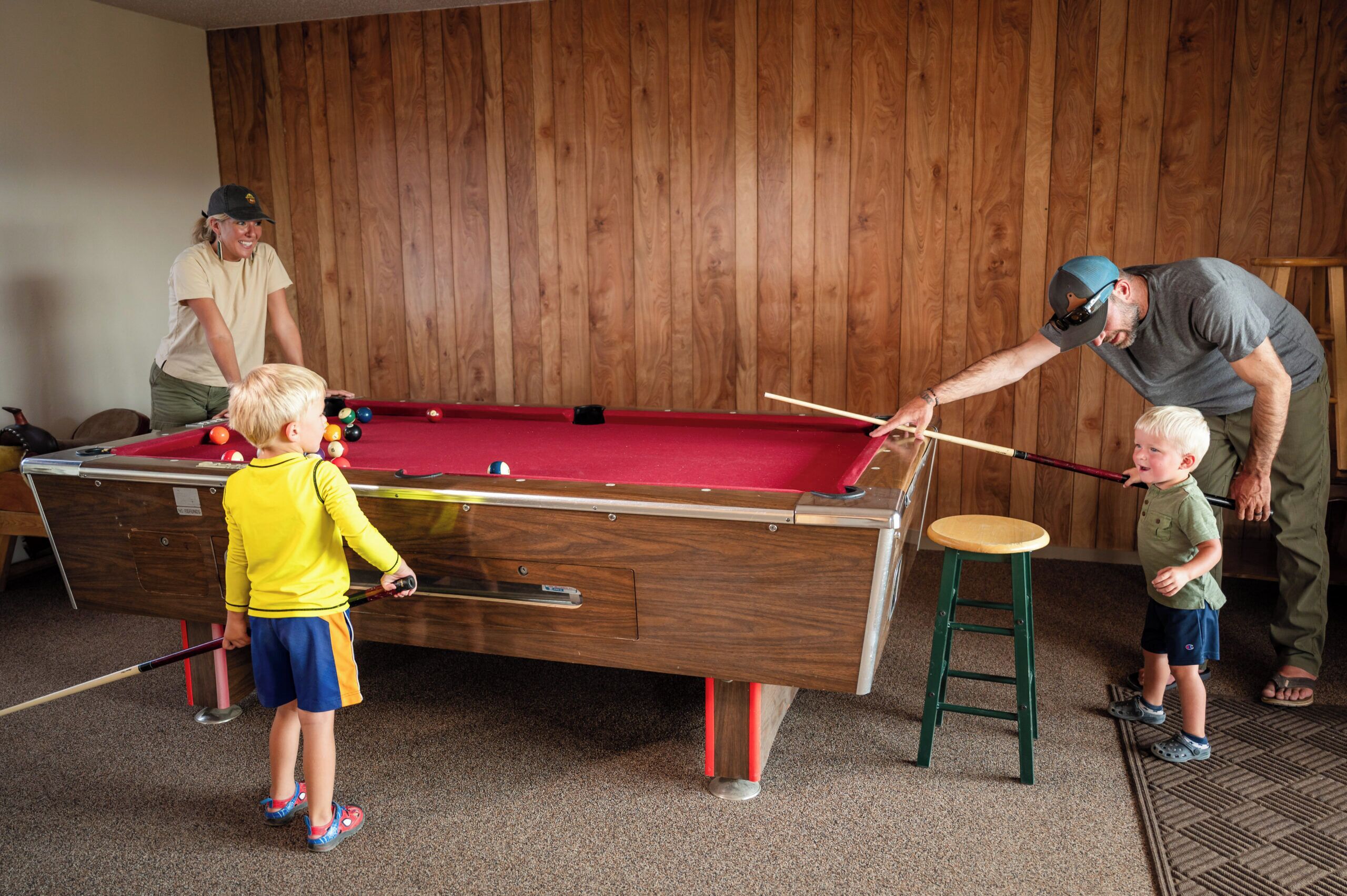 A pool table in a room with wooden paneling.