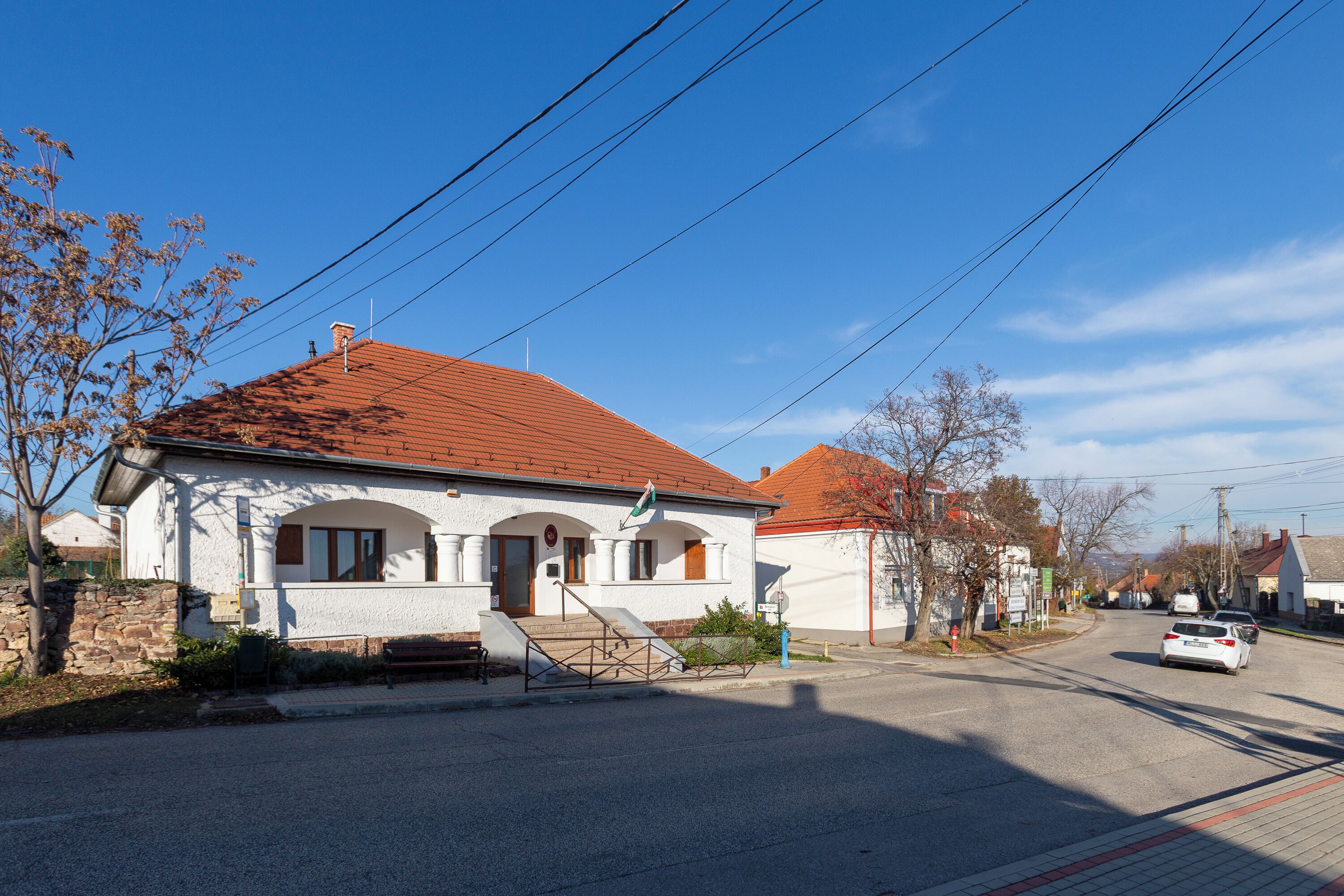 A two-story building with a red roof, a small porch, and a visible staircase leading to the entrance.