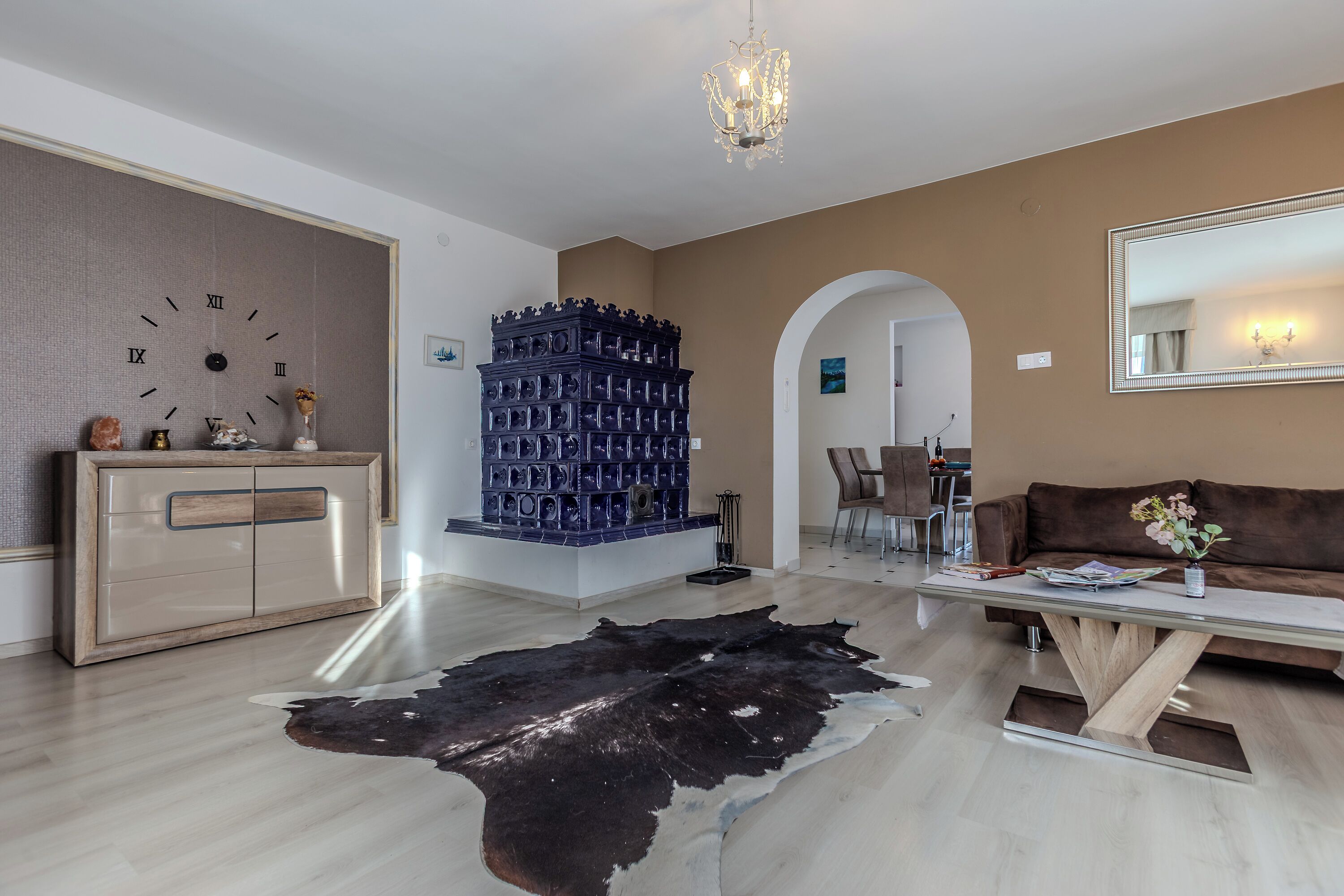 A living room with a large clock, a decorative blue structure, a sofa, and a cowhide rug.
