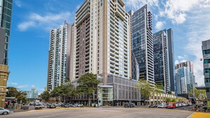 A modern urban street with high-rise buildings, a clear sky, and a pedestrian crossing. - Exclusive Stays - The Summit (Southbank)