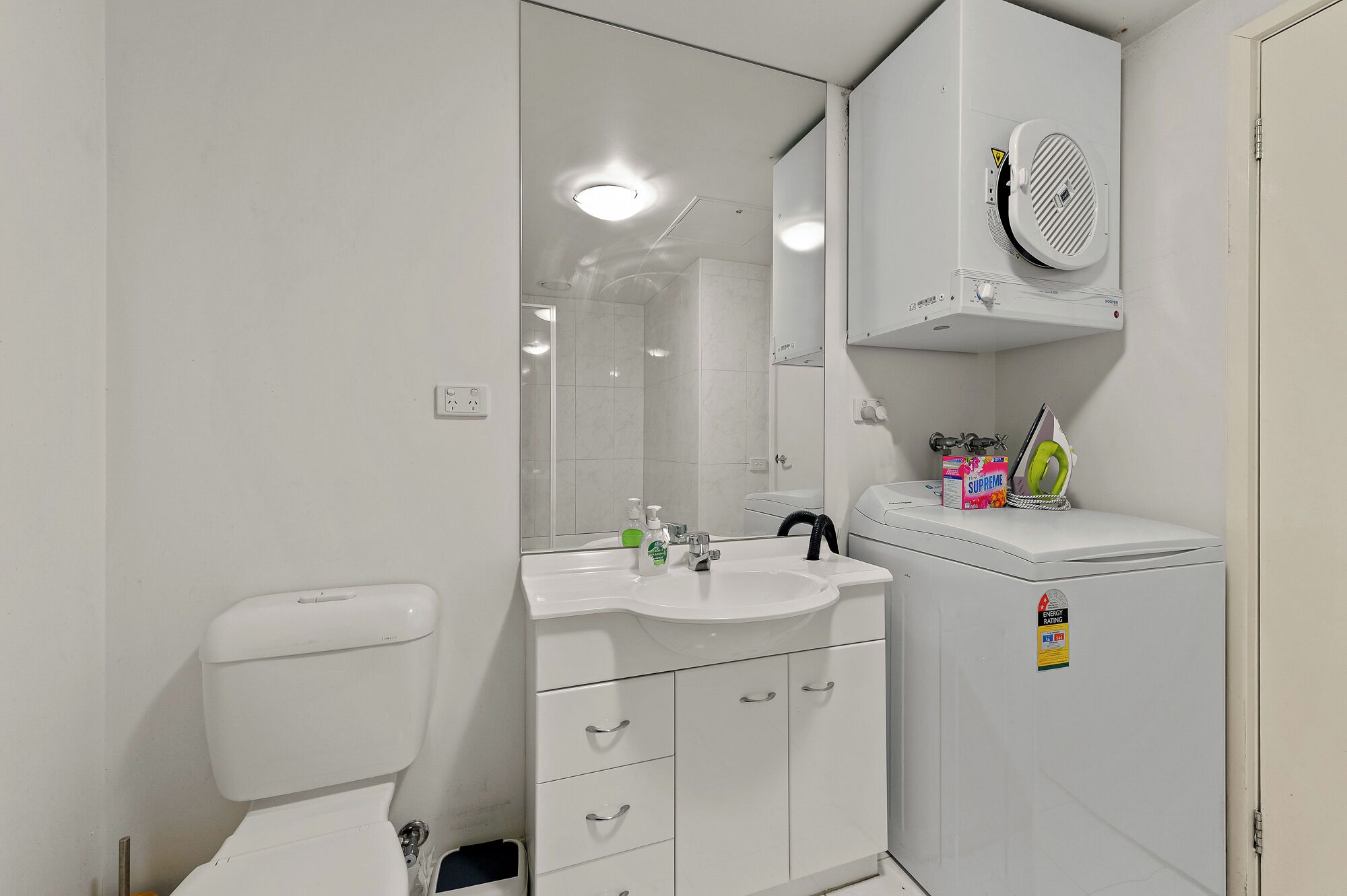 A compact bathroom with a toilet, sink, and mirror.