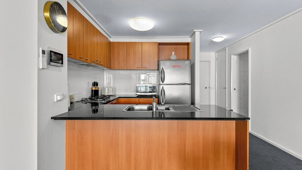 Une cuisine moderne avec des meubles en bois, des appareils électroménagers en acier inoxydable et un plan de travail noir.