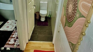 A bathroom with a toilet, a small window, and a shower area.