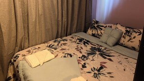 Une chambre à coucher avec un lit, des rideaux et un oreiller à motifs floraux.