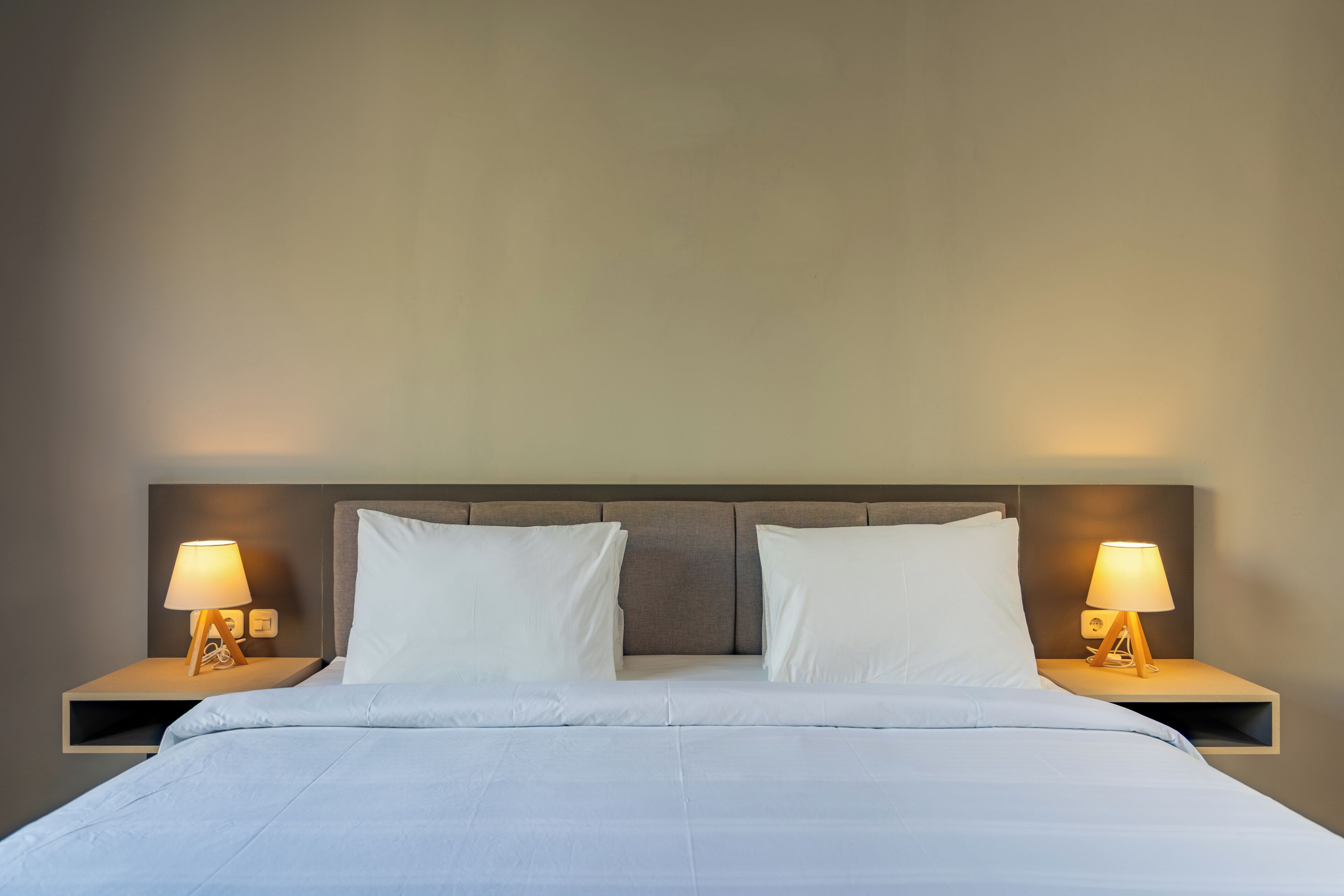 A hotel room with a bed, two bedside tables with lamps, and a headboard.