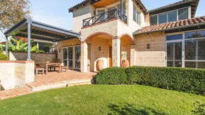 A two-story house with a patio, a covered outdoor seating area, and a well-maintained lawn.