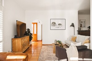 A living room with a sofa, a television, a wooden cabinet, and a framed picture on the wall.