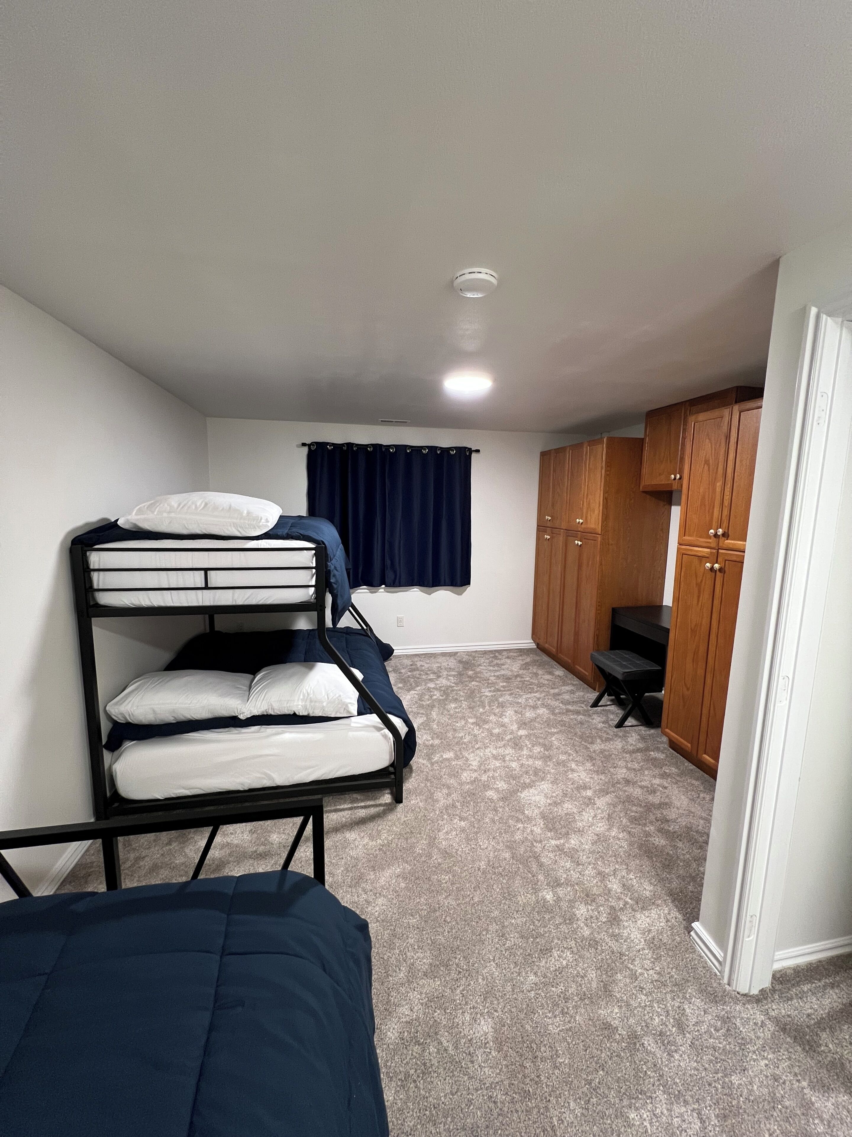 Une chambre avec des lits superposés, un bureau et une armoire.