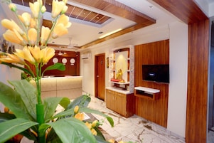A modern living room with a wooden cabinet, a flat-screen TV, and a reception desk.