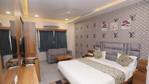 Une chambre d’hôtel équipée d’un lit, d’un bureau, d’une chaise, d’une télévision et d’un mur orné d’un motif.