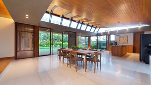 A spacious modern kitchen with a wooden ceiling, large windows, and a dining area with a table and chairs. - Indica Luxury Villa Ubud (Ubud)